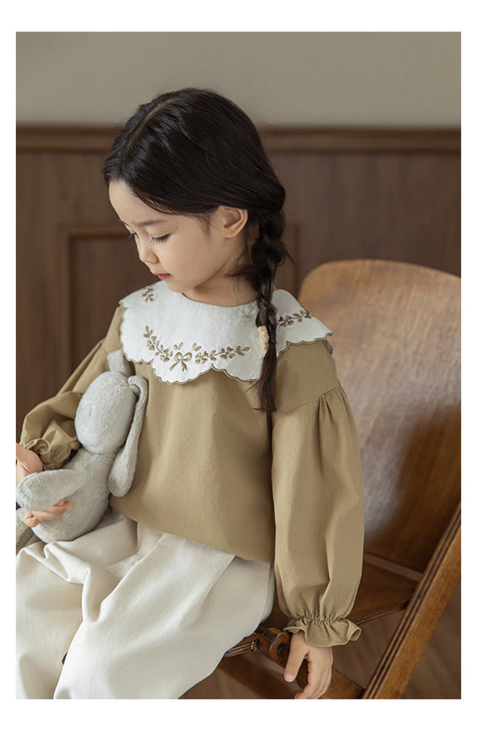 Girls wearinga akhaki cotton blouse with embroidered collar