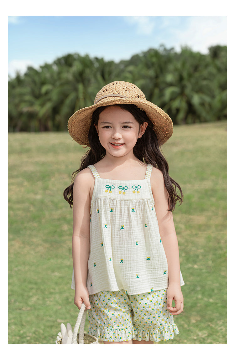 Young girl in a muslin cotton summer top and straw hat standing in a grassy field 