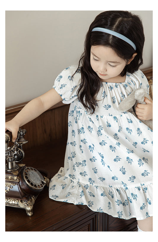 Girl wearing summer blue floral dress with square neck and puffed sleeves